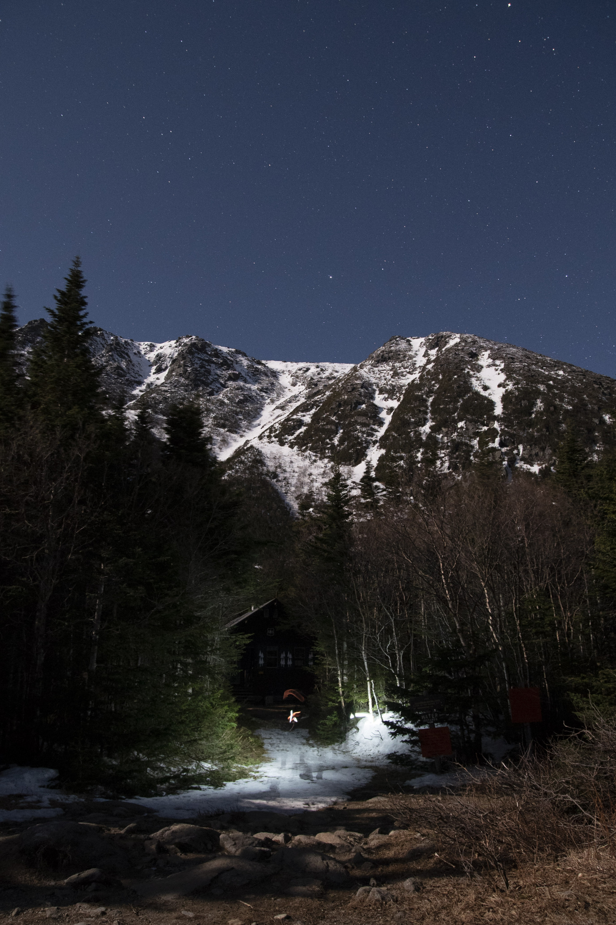 With the light from the nearly full moon painting a beautiful exposure on the brisk landscape in the White Mountains, stars are somewhat visible above the rough terrain in April 2016.